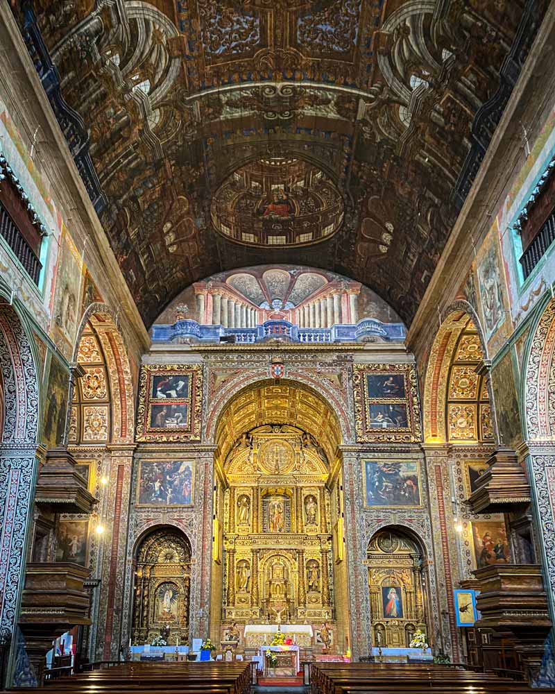 Inside a church with ornate gold and blue paintings and tiles, and a slightly curved ceiling with intricate wood work