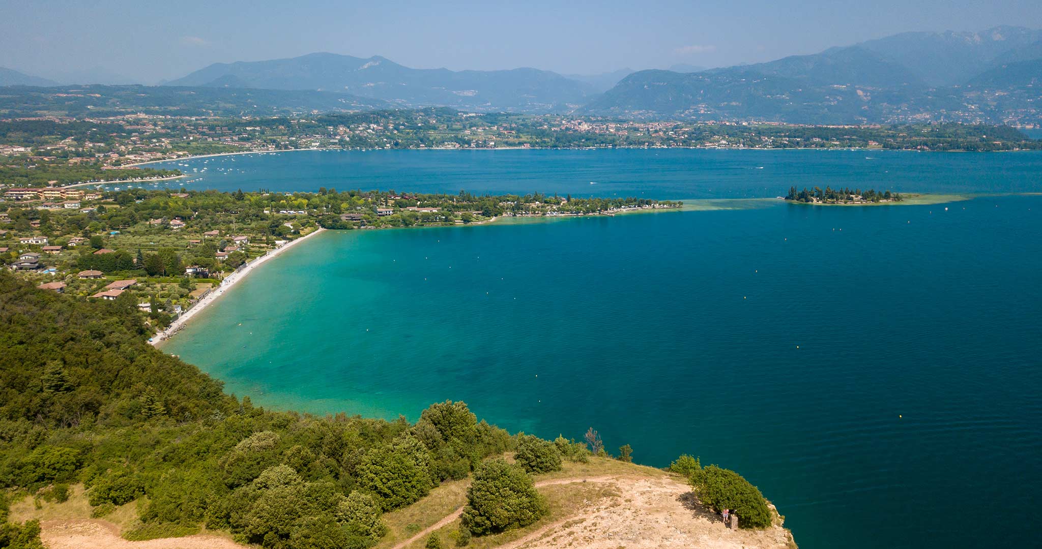 Lake Garda seen from above high up on a hill looking out on a beach and islands