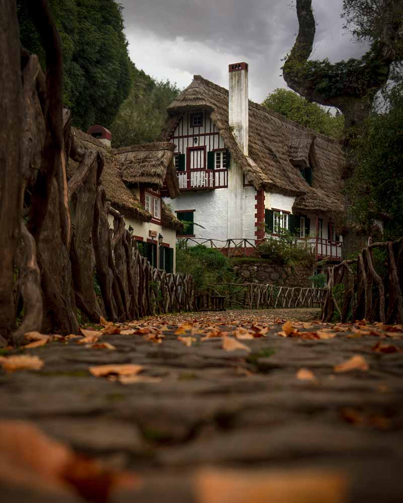 A tradtitional thatched house with autumn leaves and chimney at the start of the hiking trail