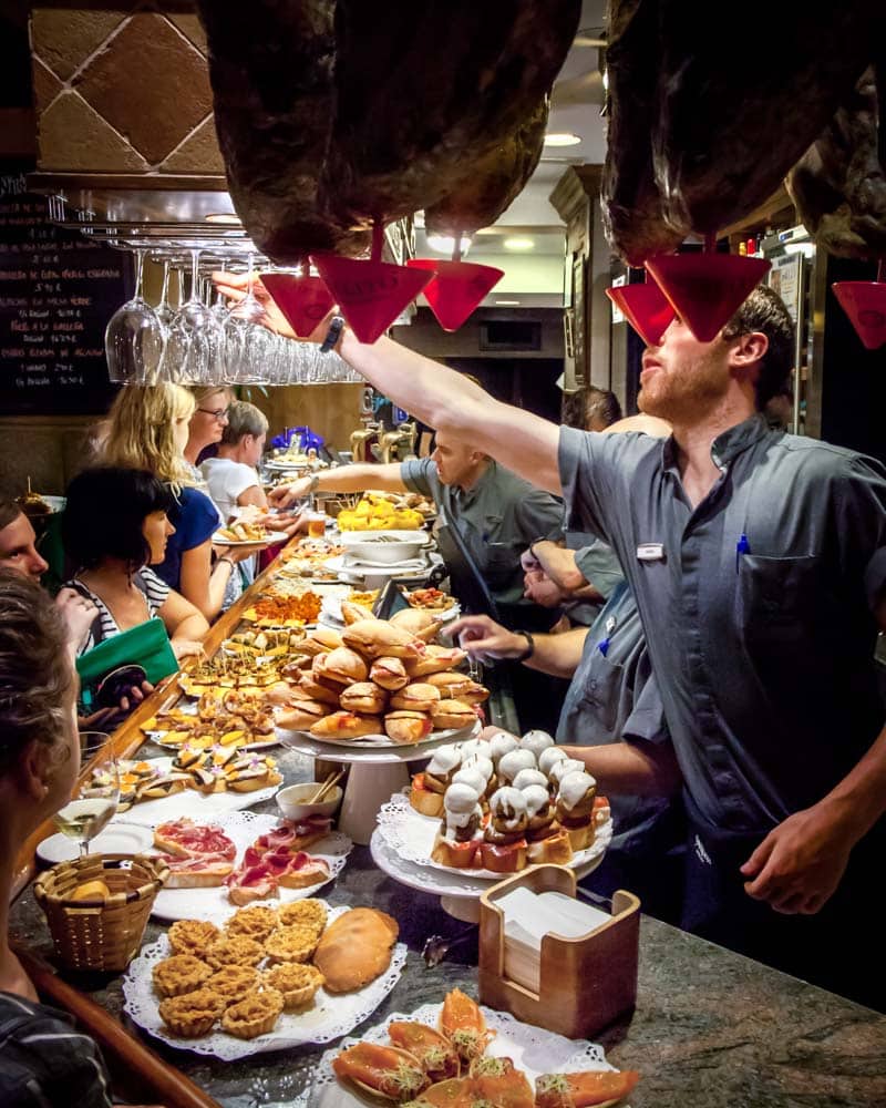 A packed bar of Pintxos and Jambon hanging down